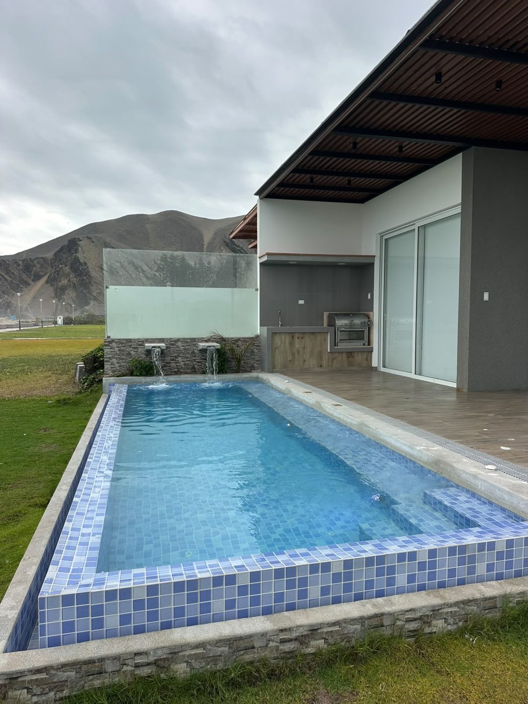 Piscina revestida con venecitas azules junto a zona de parrilla
